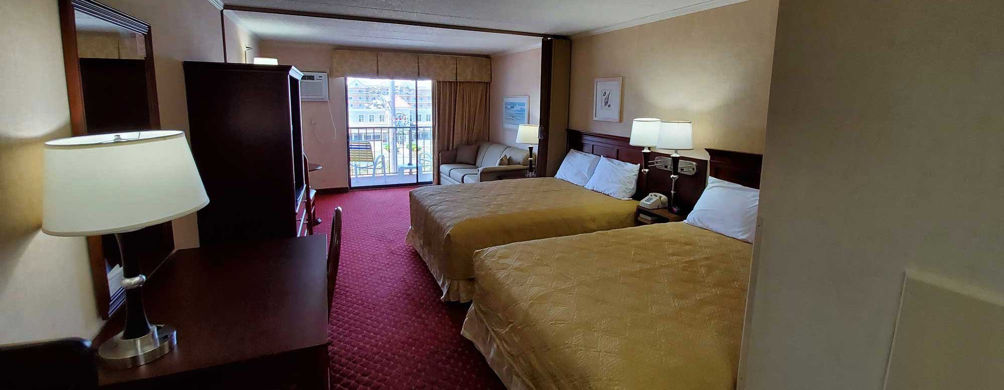 Motel room with two queen beds, dresser and balcony